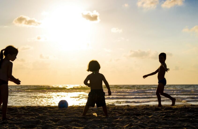silhouette of three children on beach
